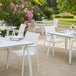 A white Grosfillex Sunset resin chair next to a white table.
