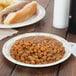 A Solo paper plate with a hot dog, beans, and a fork.