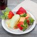 A Bare by Solo medium weight paper plate with strawberries, an orange, and a drink on it.