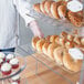 A person using a Vollrath extra large bakery tray to display bagels.