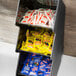 A Vollrath 3 tier condiment holder on a counter with a variety of condiments in packets.