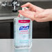 A person using a pump dispenser to apply Purell Advanced gel hand sanitizer.