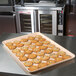 A MFG Tray 18" x 26" peach fiberglass market tray of cookies on a counter.