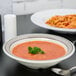 A bowl of GET Diamond Cambridge soup with a spoon on a table.