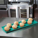 A MFG Tray mint green fiberglass display tray with muffins on it.