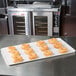 A white MFG Tray fiberglass display tray of doughnuts on a bakery counter.