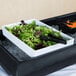 A Tablecraft white melamine bowl filled with salad on a table.