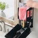 A person's hand holding a Kutol pink bag of liquid soap over a sink.