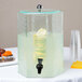 A Cal-Mil acrylic beverage dispenser filled with lemonade on a table.