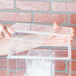 A hand holding a clear plastic lid over a clear plastic container filled with ice cubes.