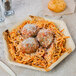 A EcoChoice palm leaf plate with spaghetti and meatballs, bread, and a drink on a table.