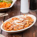 A TreeVive by EcoChoice palm leaf bowl filled with pasta and sauce on a table.