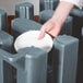 A hand placing a white plate in a grey rectangular dish dolly.