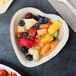 A heart shaped TreeVive palm leaf plate with fruit inside.