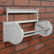 A gray steel Bulman paper dispenser on a brick wall.