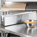 A stainless steel Edlund film and foil dispenser on a counter with a silver bowl of cereal.