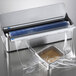 A metal Edlund film dispenser blade in a plastic bag with a roll of blue material.