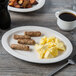 An ivory Libbey oval porcelain platter with a plate of food, a fork, and a cup of coffee.