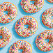 A close up of a donut with Adourne rainbow sprinkles on top.