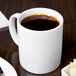 A white Libbey porcelain mug filled with coffee on a table.