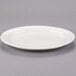 An ivory Libbey oval medium rim porcelain platter on a gray surface.