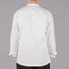 The back of a Mercer Culinary white chef jacket with black piping.