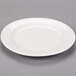 A Libbey ivory porcelain plate with a rim on a gray surface.