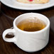 A Libbey ivory porcelain stacking cup filled with tea on a table.