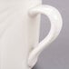 A close-up of a Libbey ivory porcelain mug with a curved handle.