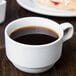 A Libbey white porcelain china cup filled with coffee on a table.