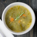 A Libbey ivory porcelain bouillon bowl filled with soup and a sprig of rosemary.