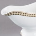 A white bone china gravy boat with a gold trim.
