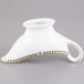 A white porcelain Syracuse China Baroque sauce boat with gold trim.