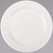A close up of a Libbey ivory porcelain plate with a curved rim on a gray surface.