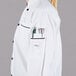 A woman wearing a white Mercer Culinary chef coat with black piping.