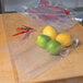 A plastic bag filled with lemons, limes, and red peppers on a table.