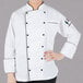 A woman wearing a white Mercer Culinary chef's coat with black piping.