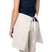 A woman wearing an ivory Intedge waist apron with a pocket.