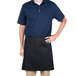 A man wearing an Intedge black waist apron in a professional kitchen.