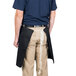 A man wearing a black Intedge waist apron with tan details.