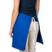 A woman wearing a blue Intedge waist apron with a white belt.