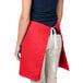 A woman wearing a red Intedge waist apron with a pocket.