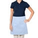 A woman wearing a light blue Intedge waist apron over a blue shirt.