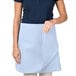 A woman wearing a light blue Intedge waist apron with a pocket.