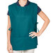 A woman wearing a teal Intedge cobbler apron with two pockets.