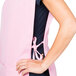 A woman wearing an Intedge pink cobbler apron with a black tie over a pink shirt.
