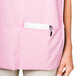 A woman wearing a pink Intedge cobbler apron with pockets.