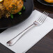 A Libbey stainless steel dinner fork on a plate of food.