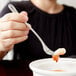 A woman using a Libbey stainless steel cocktail fork to eat food.