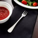 A Libbey stainless steel cocktail fork next to a bowl of red sauce.